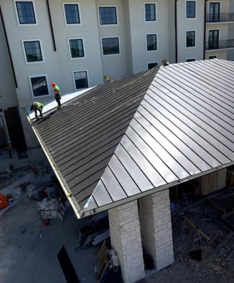 Crew installing standing seam metal roof panels on a commercial project in Altoona